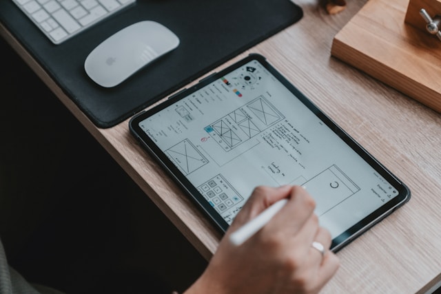 Person sketching UX wireframe on a tablet.